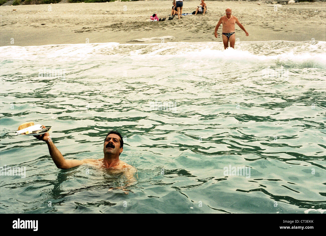 Alanya, uomo nuota nel mare con una piastra piena Foto Stock