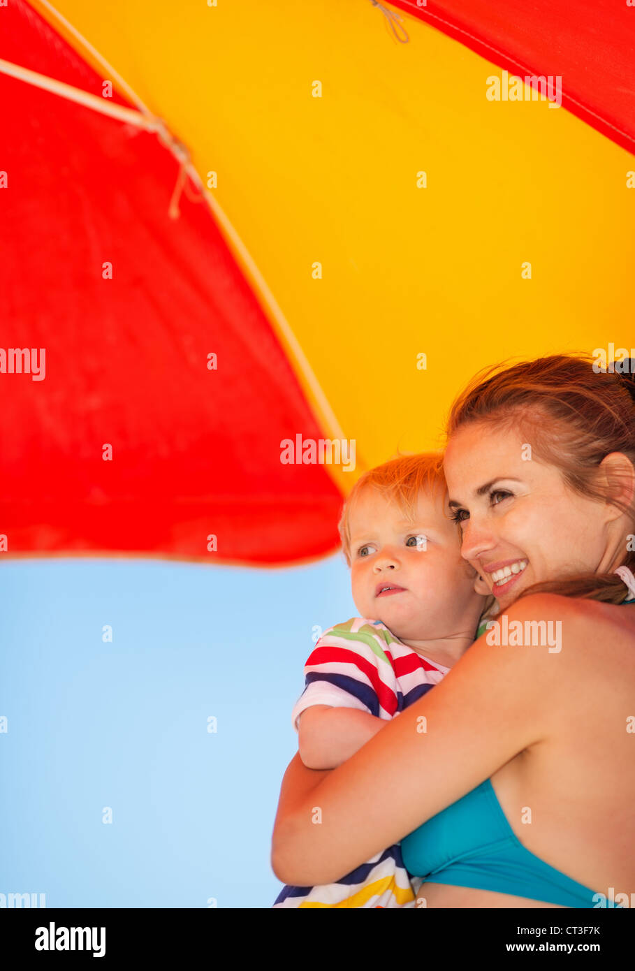 La madre e il bambino cerca su copia spazio sulla spiaggia sotto ombrellone Foto Stock