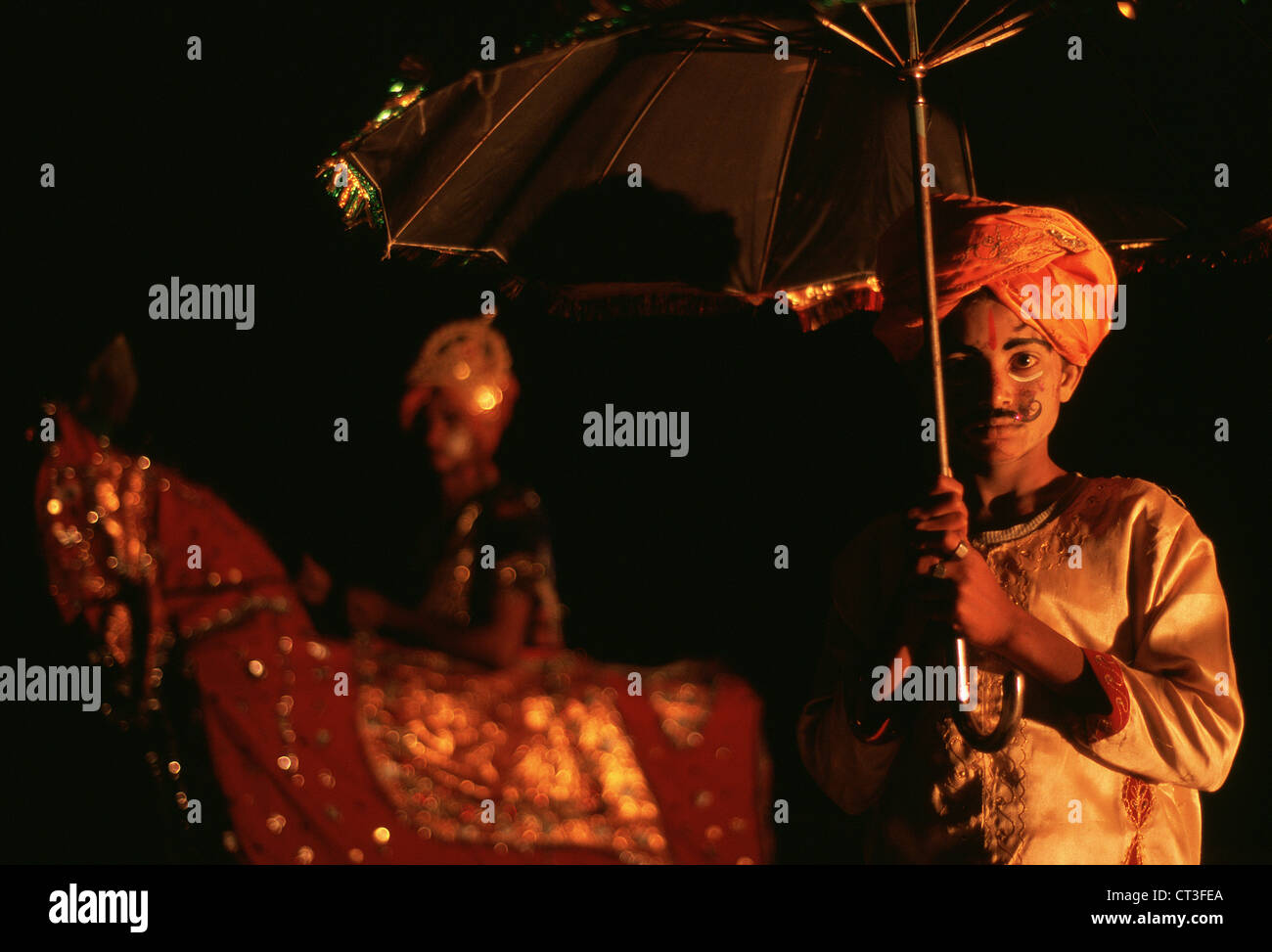 Ragazzo indù appartenenti ad una danza tradizionale di banda. Dietro di lui, il ballerino principale è in piedi con un cavallo finto ( India) Foto Stock