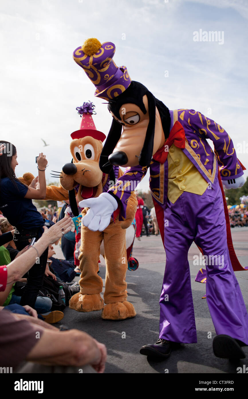 Pippo e Plutone stringono le mani di visitatori durante la street parade di Magic Kingdom, Disney World, a Orlando, Florida Foto Stock