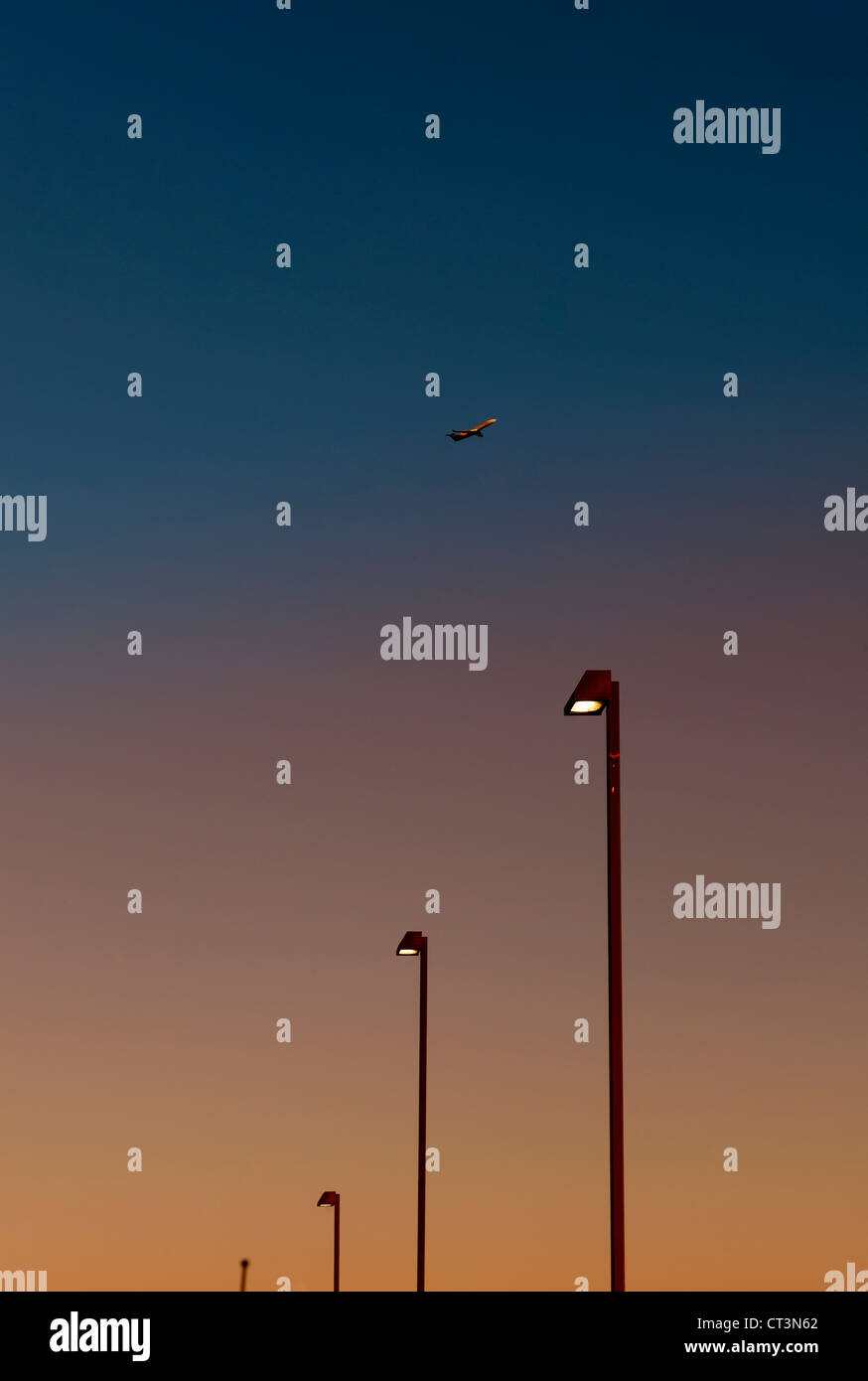 Aeroplano sopra le luci di strada al tramonto Foto Stock