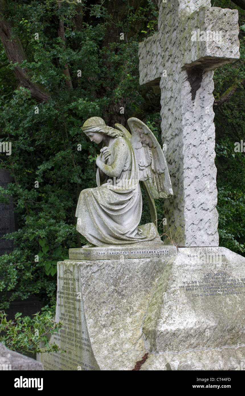 Victoian pietra di un monumento di un angelo si inchinano davanti a una croce. Foto Stock