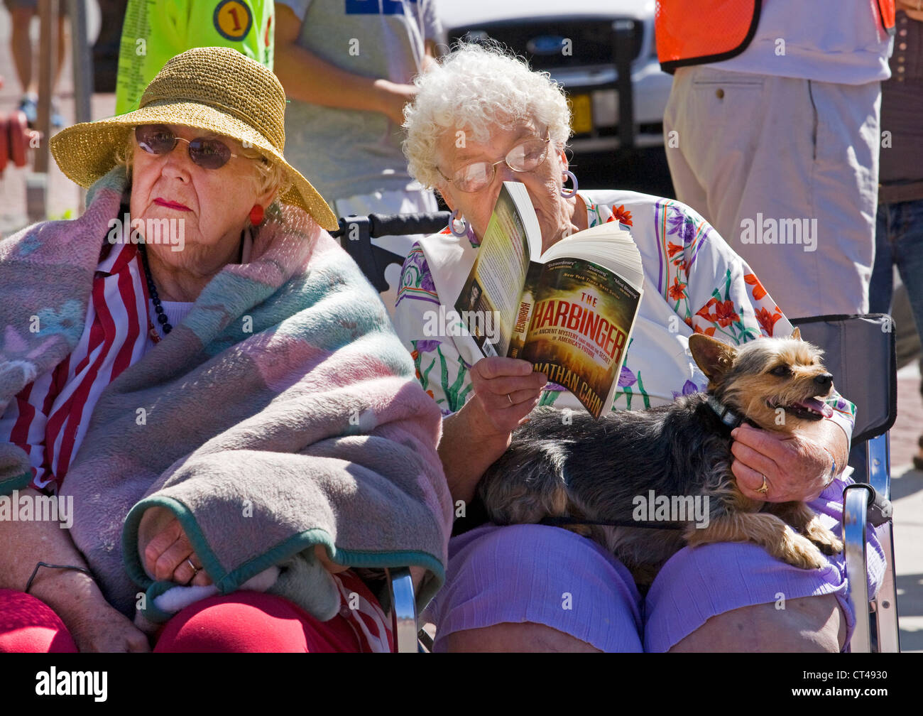 Due donne anziane in attesa per una sfilata durante la lettura di un romanzo Foto Stock