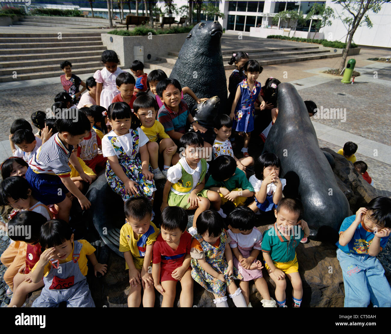 Singapore. Bambini che giocano sulla statua di guarnizioni di tenuta al di fuori del World Trade Center. Foto Stock