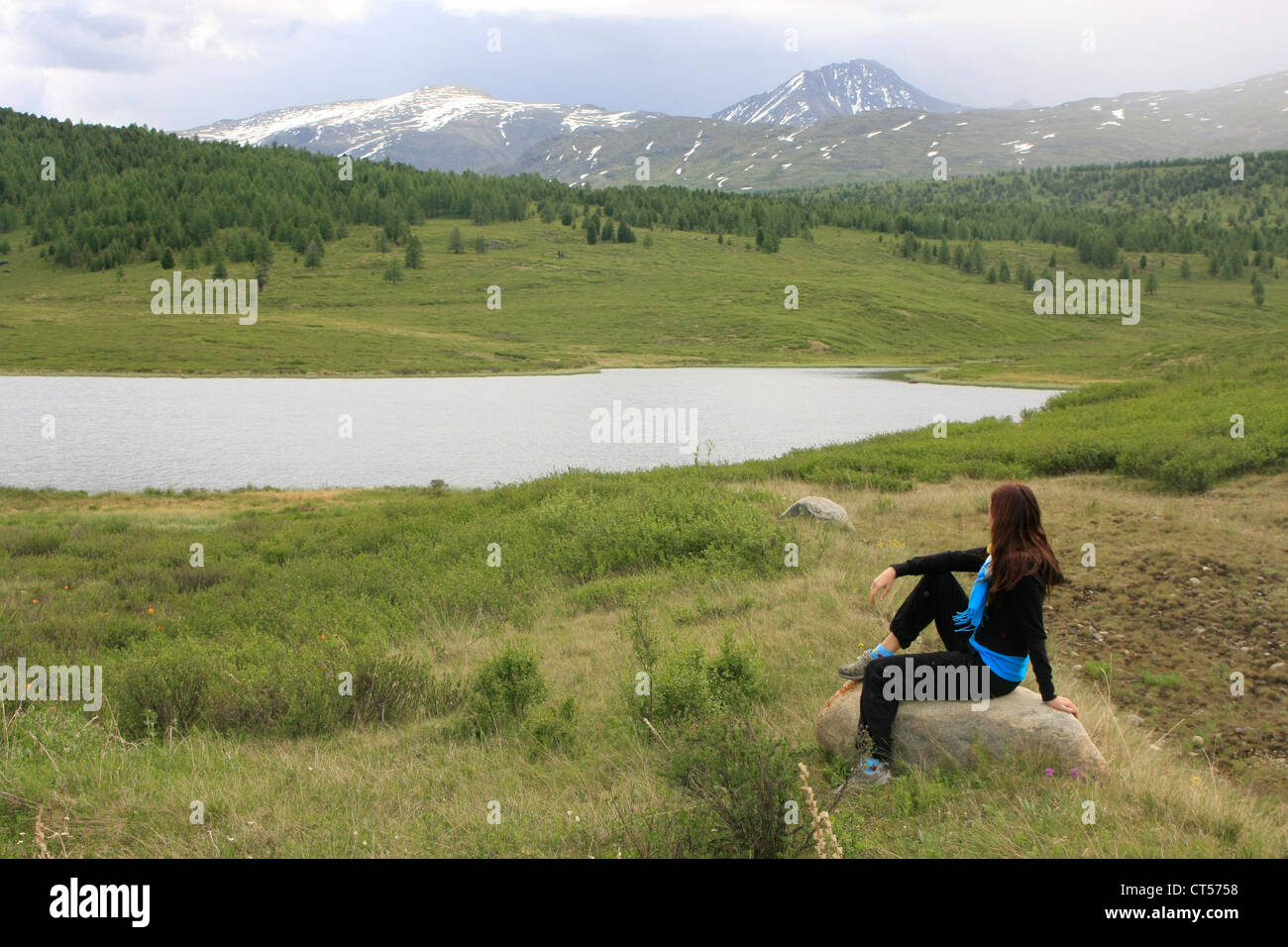 Donna ammirando esteso panorama del lago di montagna e picchi, Ulaganskoe altopiano, Altai, Siberia, Russia Foto Stock