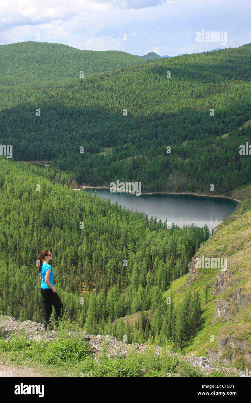 Donna ammirando vista del lago di montagna circondato da incontaminata foresta di pini, Altai, Siberia, Russia Foto Stock
