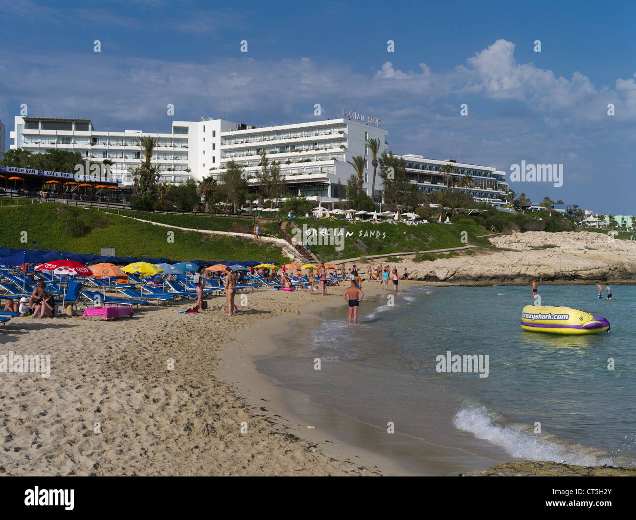 dh Gregian Bay AYIA NAPA CYPRUS Gregian Sands Hotel e spiaggia di sabbia pubblica con bagnanti turistici spiagge soleggiate Foto Stock