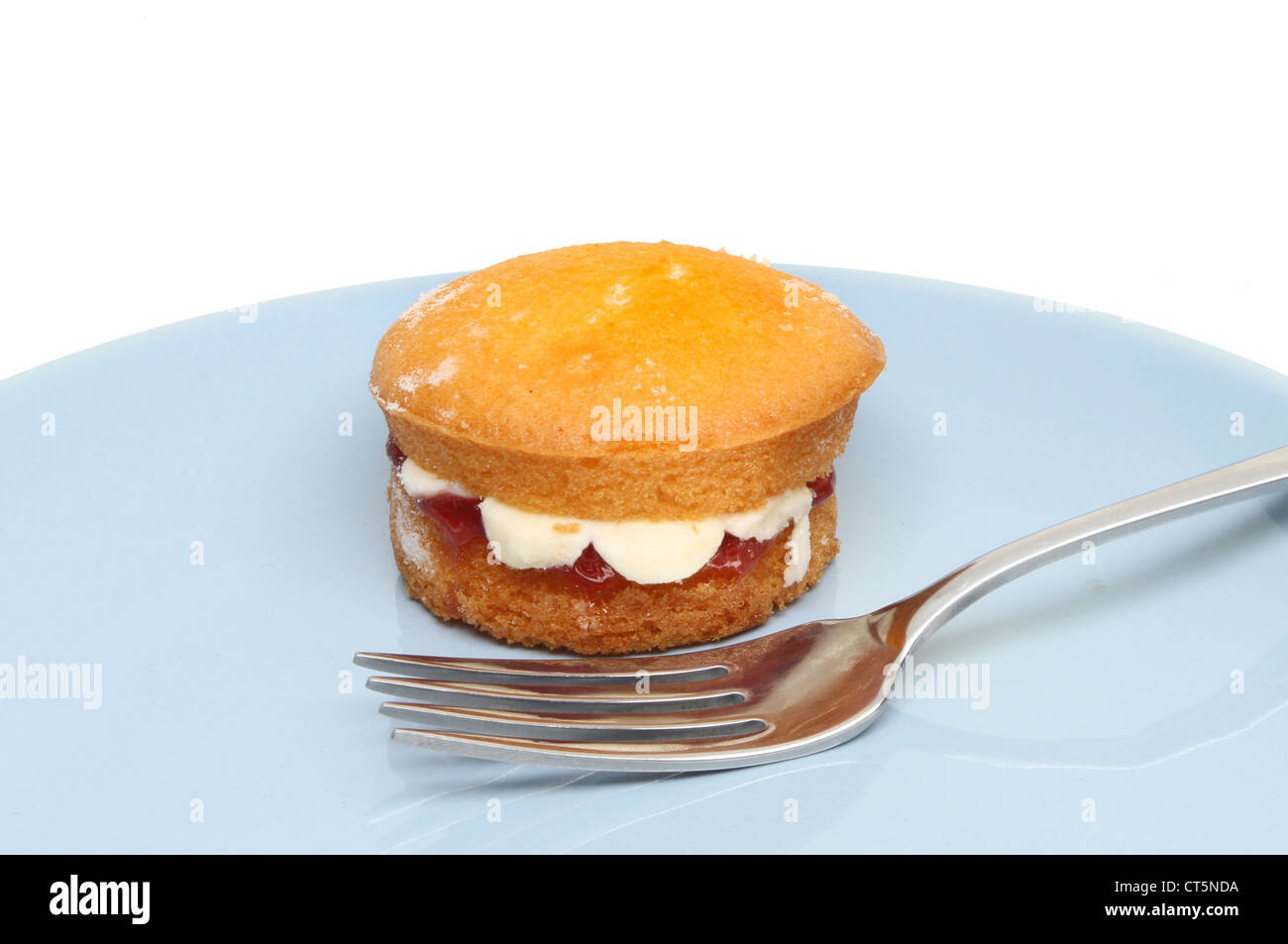 Mini victoria sponge cake su una piastra blu con una forcella Foto Stock