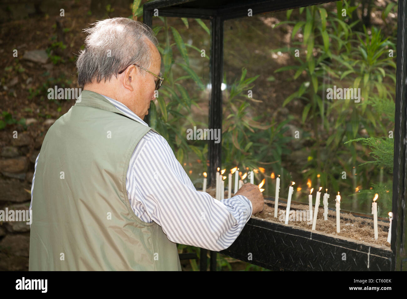 L'uomo accendendo candele al di fuori della casa della Vergine Maria, Meryemana, vicino a Efeso e Selcuk, Turchia Foto Stock