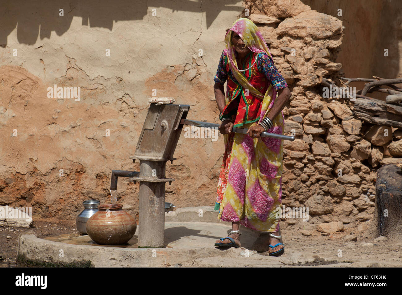 Donna di Rajasthani pompe acqua a un bene Foto Stock