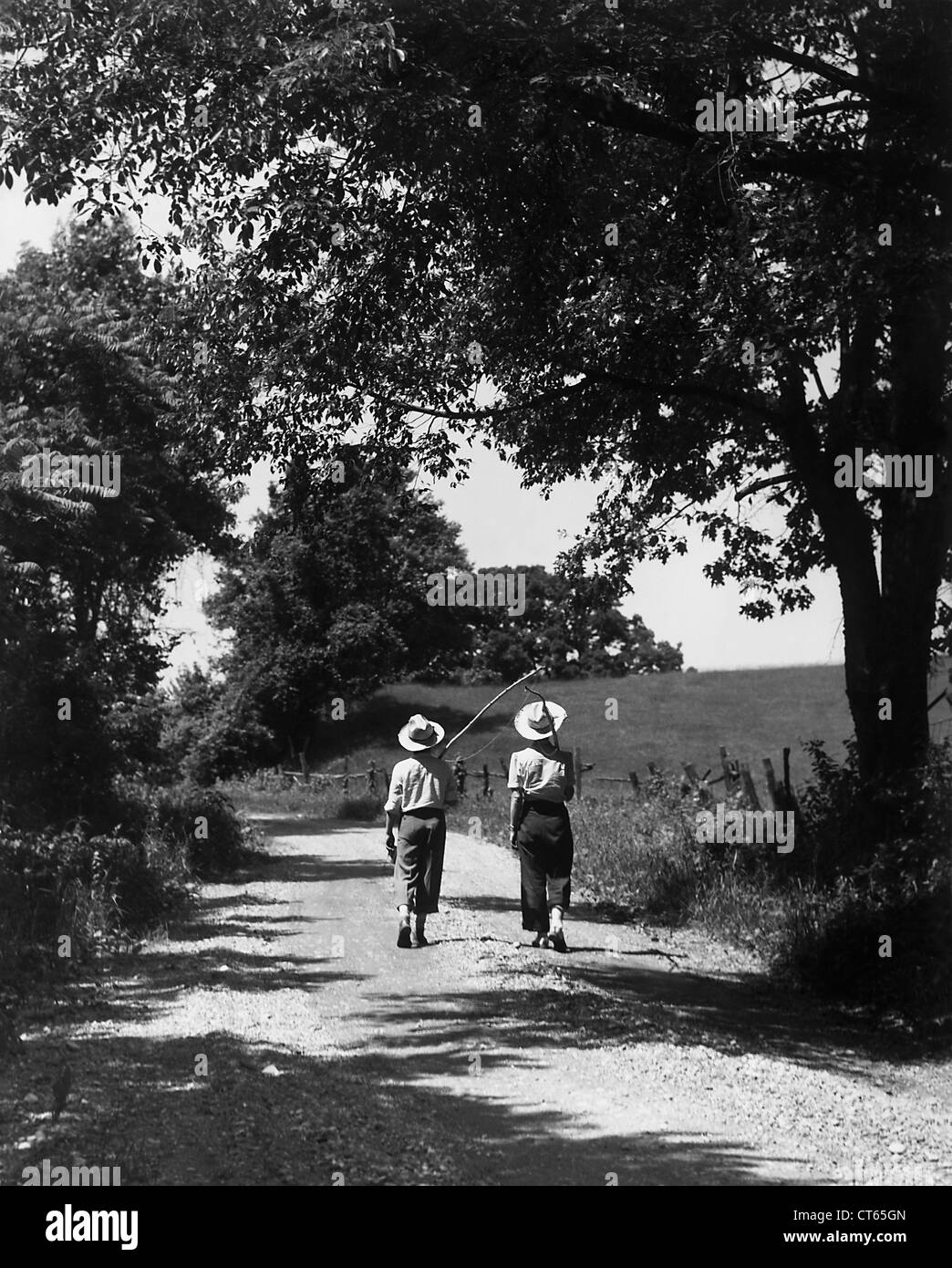 Ragazzi camminare per strada rurale con poli di pesca Foto Stock