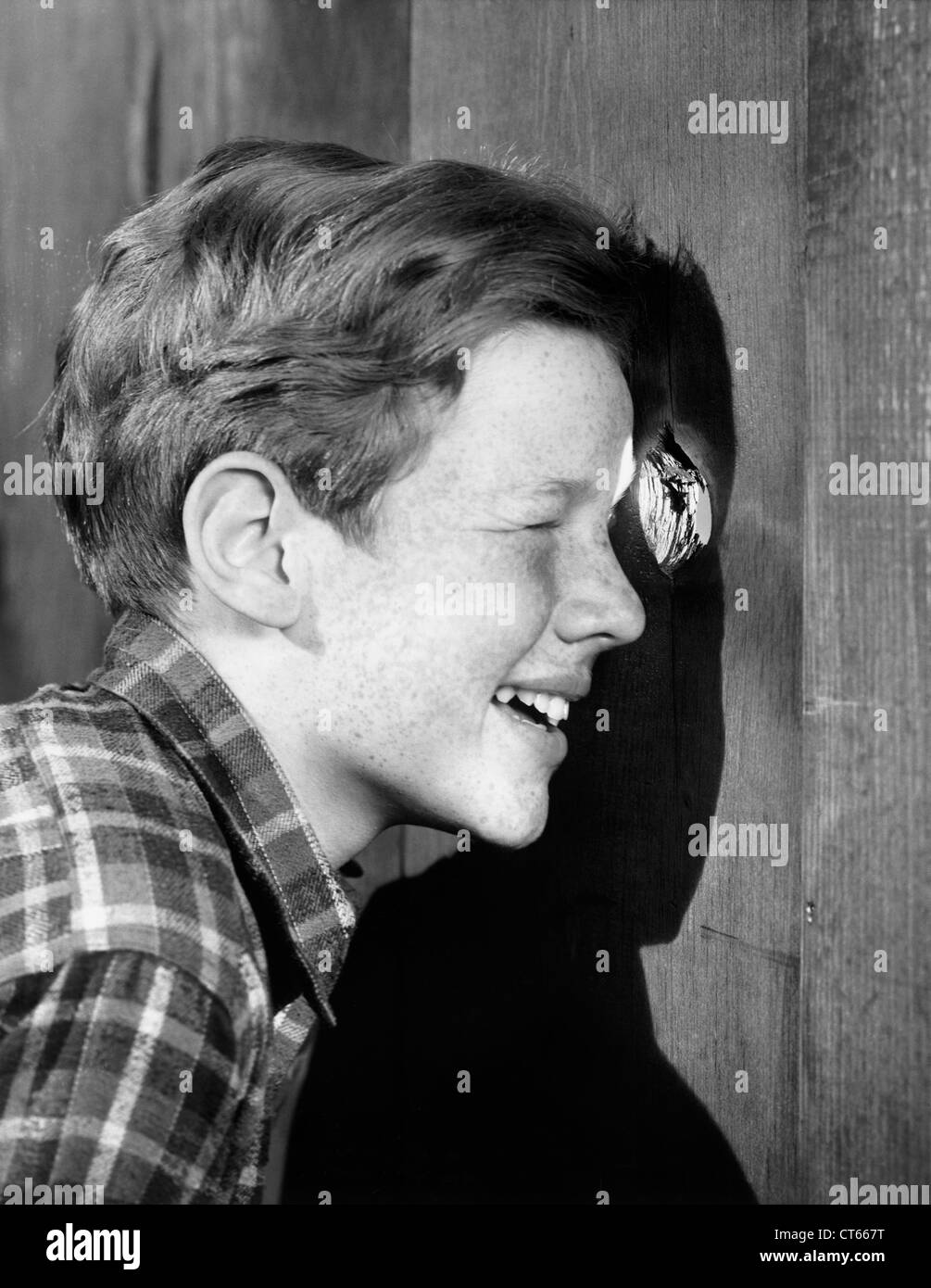 Ragazzo spiata attraverso il foro nel recinto. Foto Stock