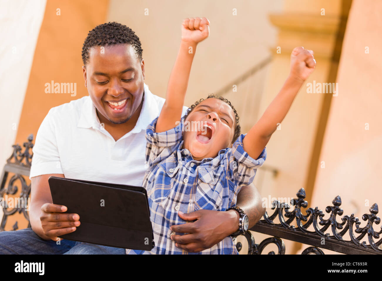 Felice americano africano padre e di razza mista figlio divertirsi usando il Touch Pad computer Tablet all'esterno. Foto Stock