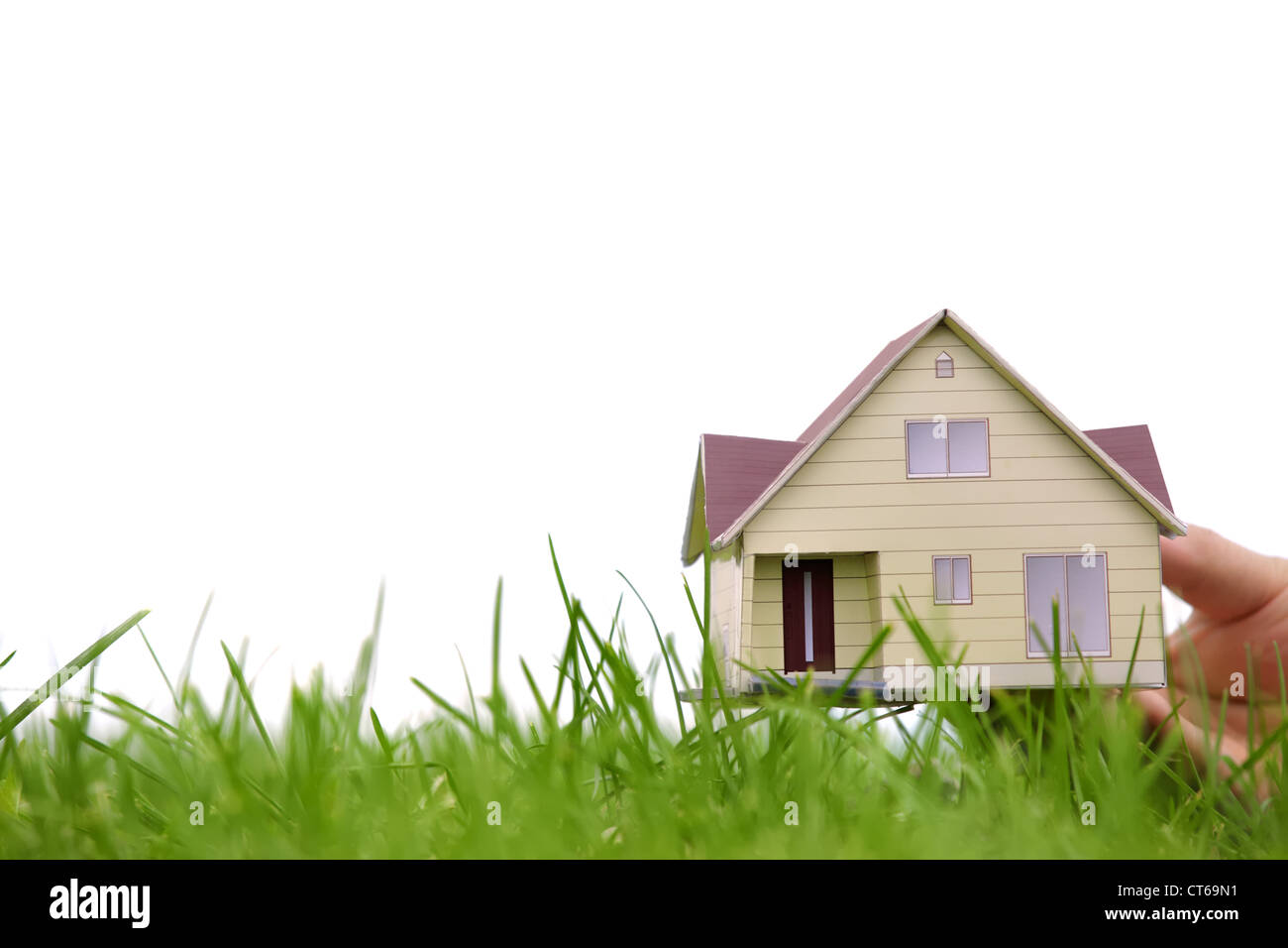 Mano che regge il modello di una casa su erba verde,concetto. Foto Stock