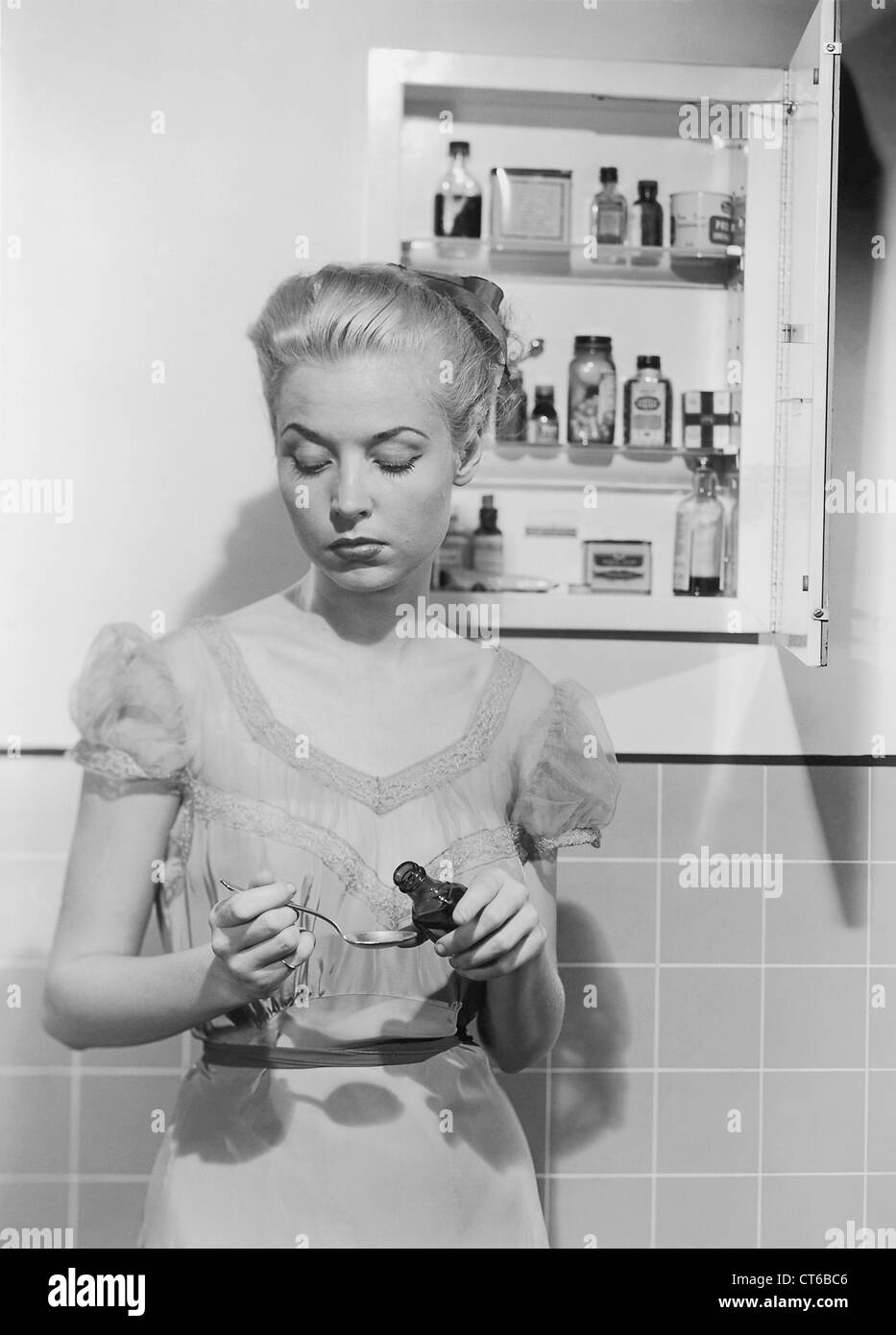 Donna di prendere la medicina nel davanti del cabinet Foto Stock