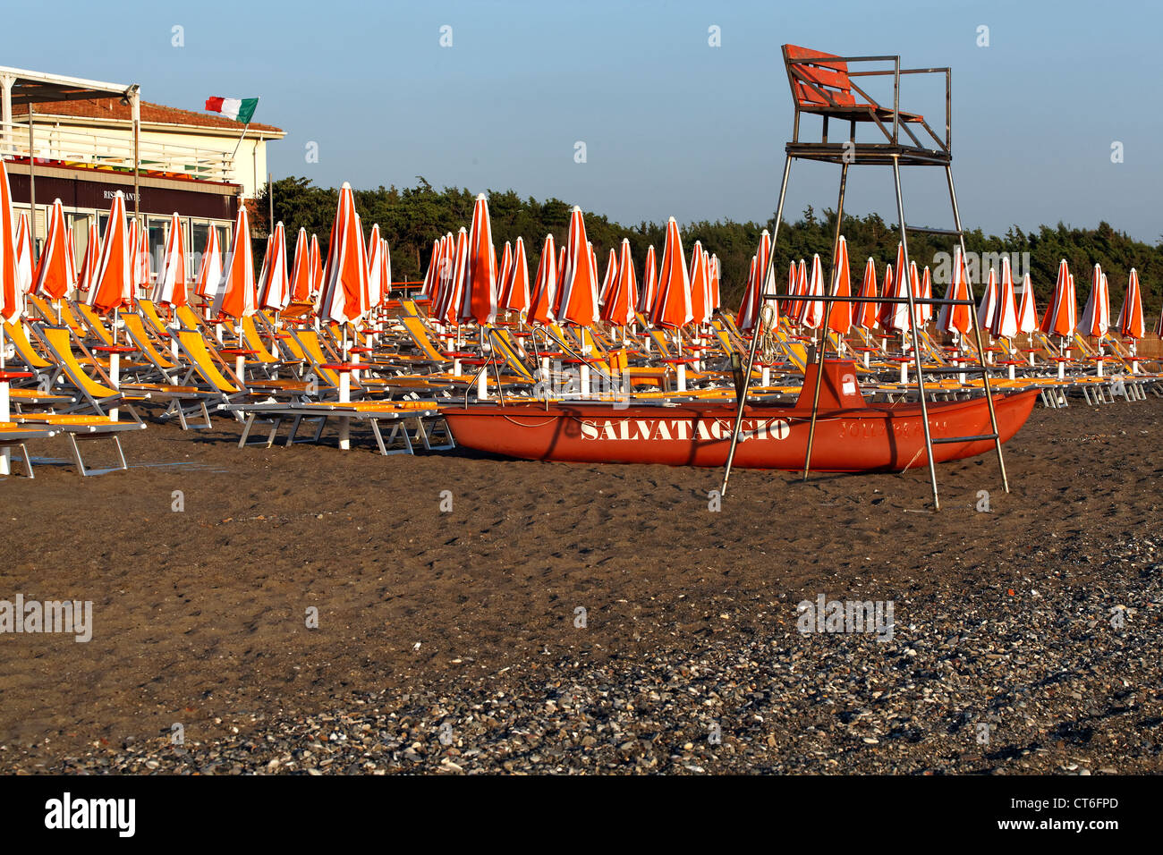 Chiuso di ombrelloni e sedie a sdraio vita torre di guardia con barca vita su una spiaggia italiana, Bibbona Toscana Italia Foto Stock