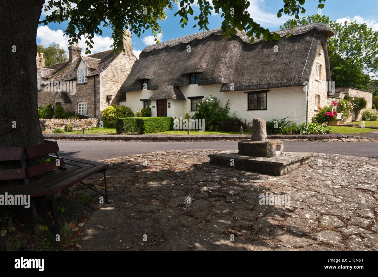 La pietra e la sterpaglia cottages accanto a resti di una croce di pietra nel centro di Edith Weston, Rutland, Inghilterra Foto Stock