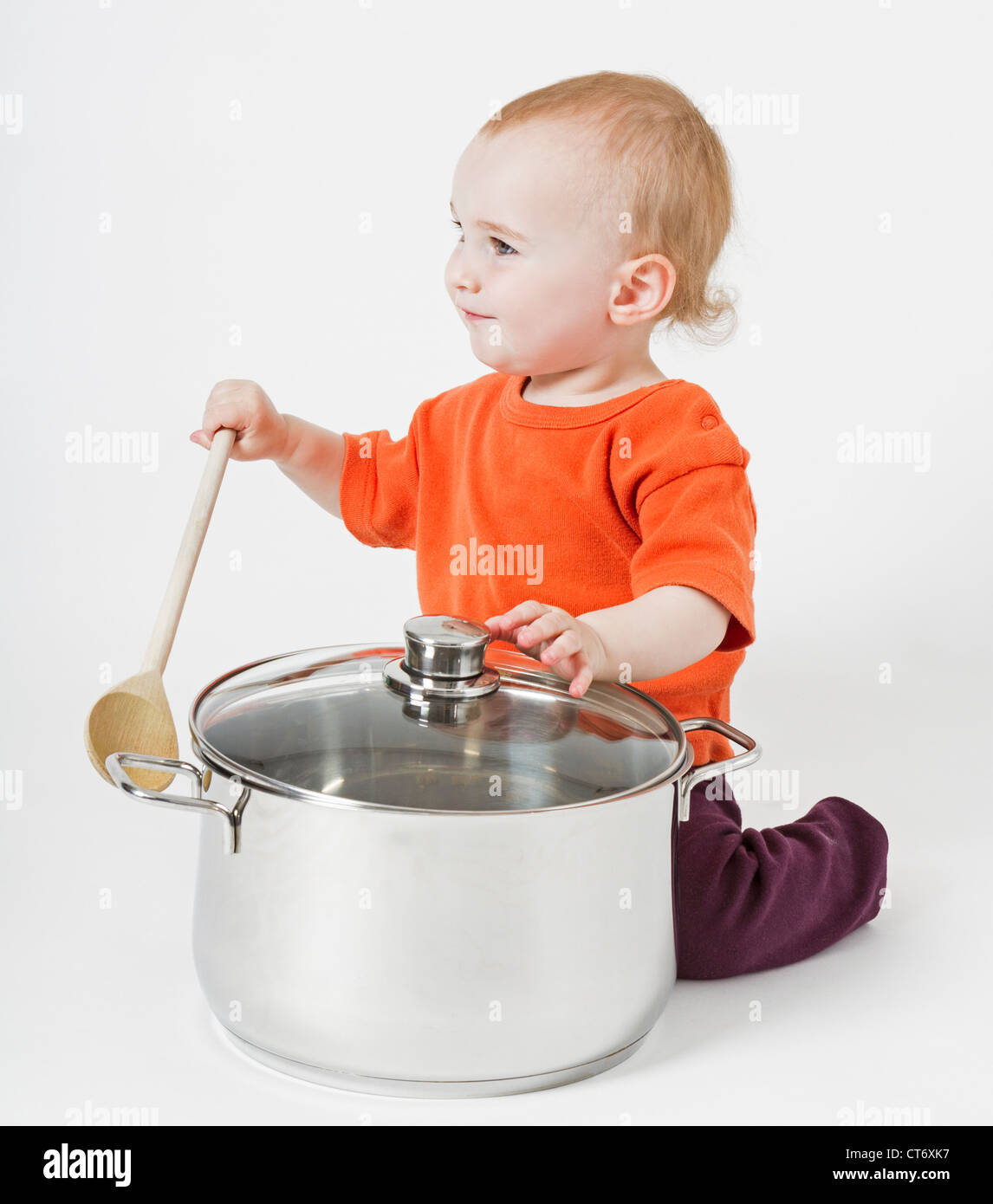 Bambino con grande pentola di cottura e il cucchiaio di legno su sfondo neutro Foto Stock