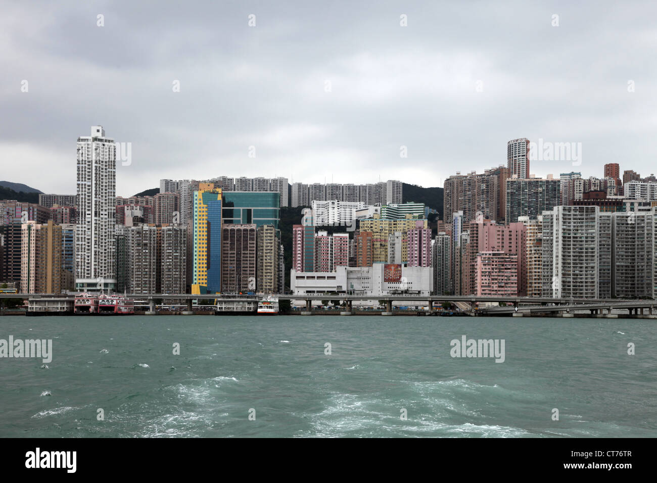 Si tratta di una foto del Victoria Harbour in Hong Kong. È possibile vedere l'oceano, torri, battello, traghetto, delle montagne e della città della città Foto Stock