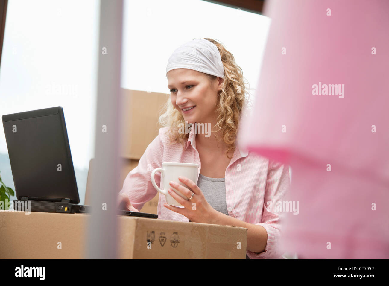 Giovane donna con computer portatile nella nuova casa Foto Stock