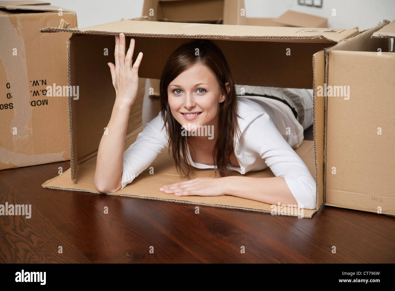 Giovane donna giacente in una scatola di cartone Foto Stock