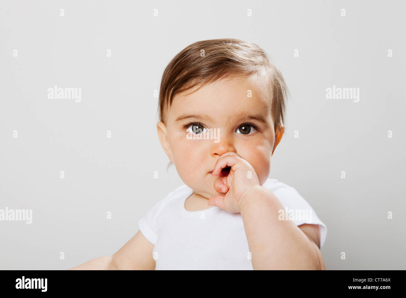 Baby boy guardando la telecamera a mano e bocca di copertura Foto Stock