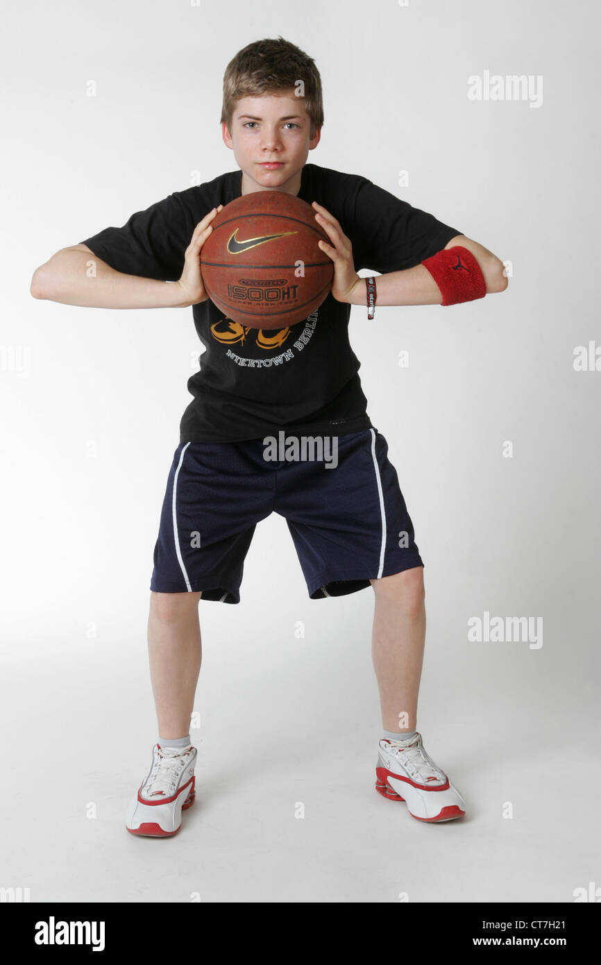 Un ragazzo pone con una palla da basket Foto Stock