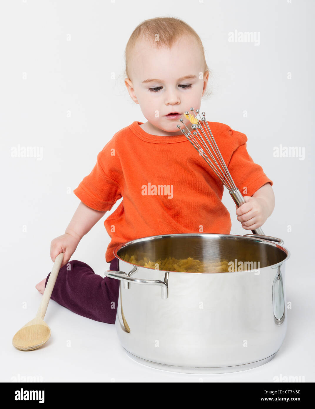 Bambino con grande pentola di cottura su sfondo grigio neutro Foto Stock