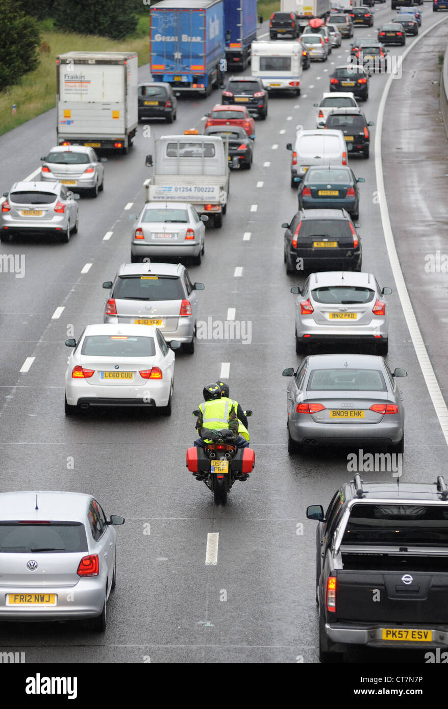 Un motociclo filtri attraverso il traffico pesante sulla autostrada M6 vicino a Stafford sicurezza nuovamente DUE RUOTE AD ALTA VISIBILITÀ REGNO UNITO Foto Stock