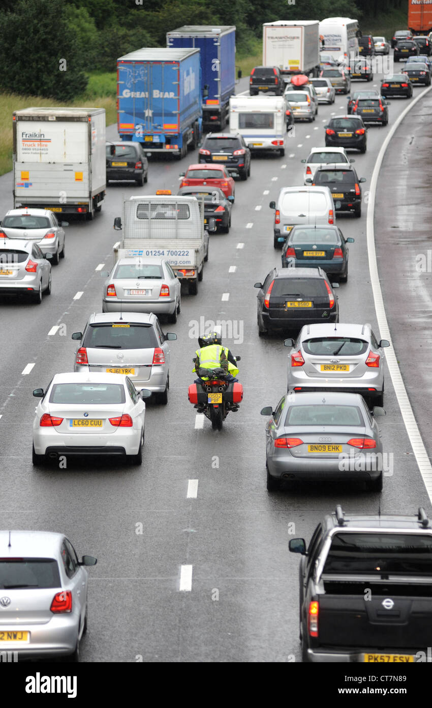 Un motociclo filtri attraverso il traffico pesante sulla autostrada M6 vicino a Stafford code nuovamente la visibilità degli inceppamenti BIKERS DI TRASPORTO ETC REGNO UNITO Foto Stock