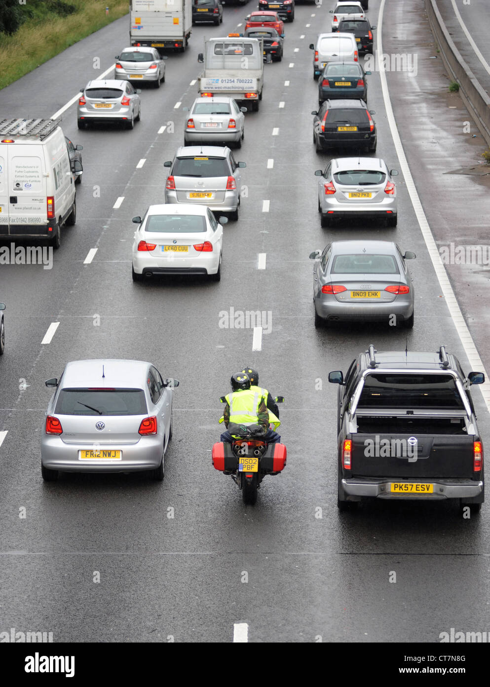 Un motociclo filtri attraverso il traffico pesante sulla autostrada M6 vicino a Stafford sicurezza nuovamente DUE RUOTE AD ALTA VISIBILITÀ REGNO UNITO Foto Stock
