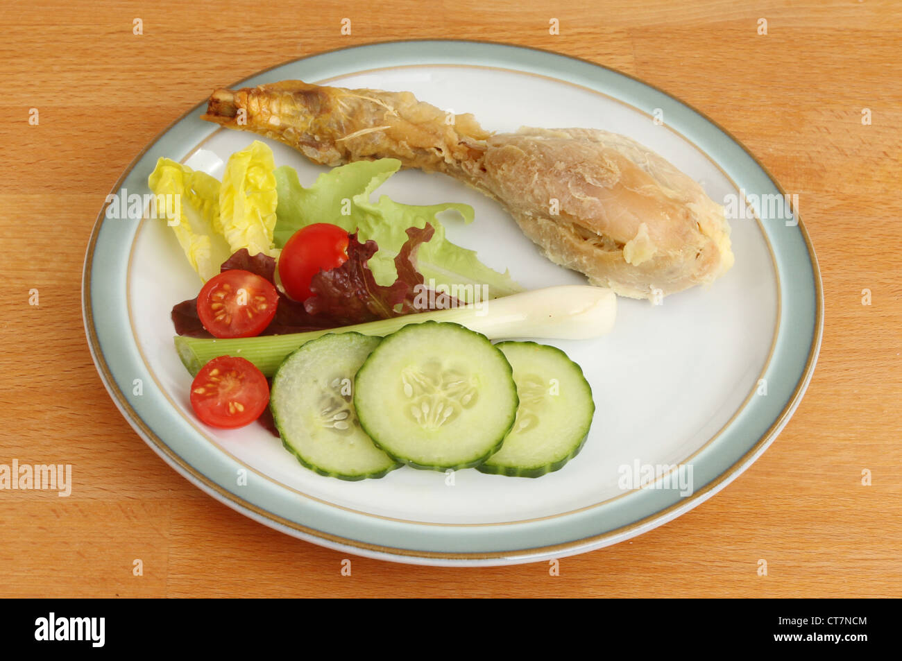 Coscia di pollo con insalata su una piastra su una superficie in legno Foto Stock