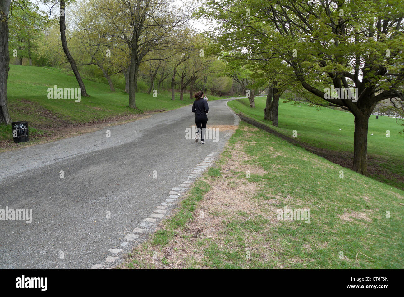 Una donna fare jogging lungo un percorso di cenere nel Parc Jeanne-Mance nella primavera di Montreal, Quebec, Canada Foto Stock