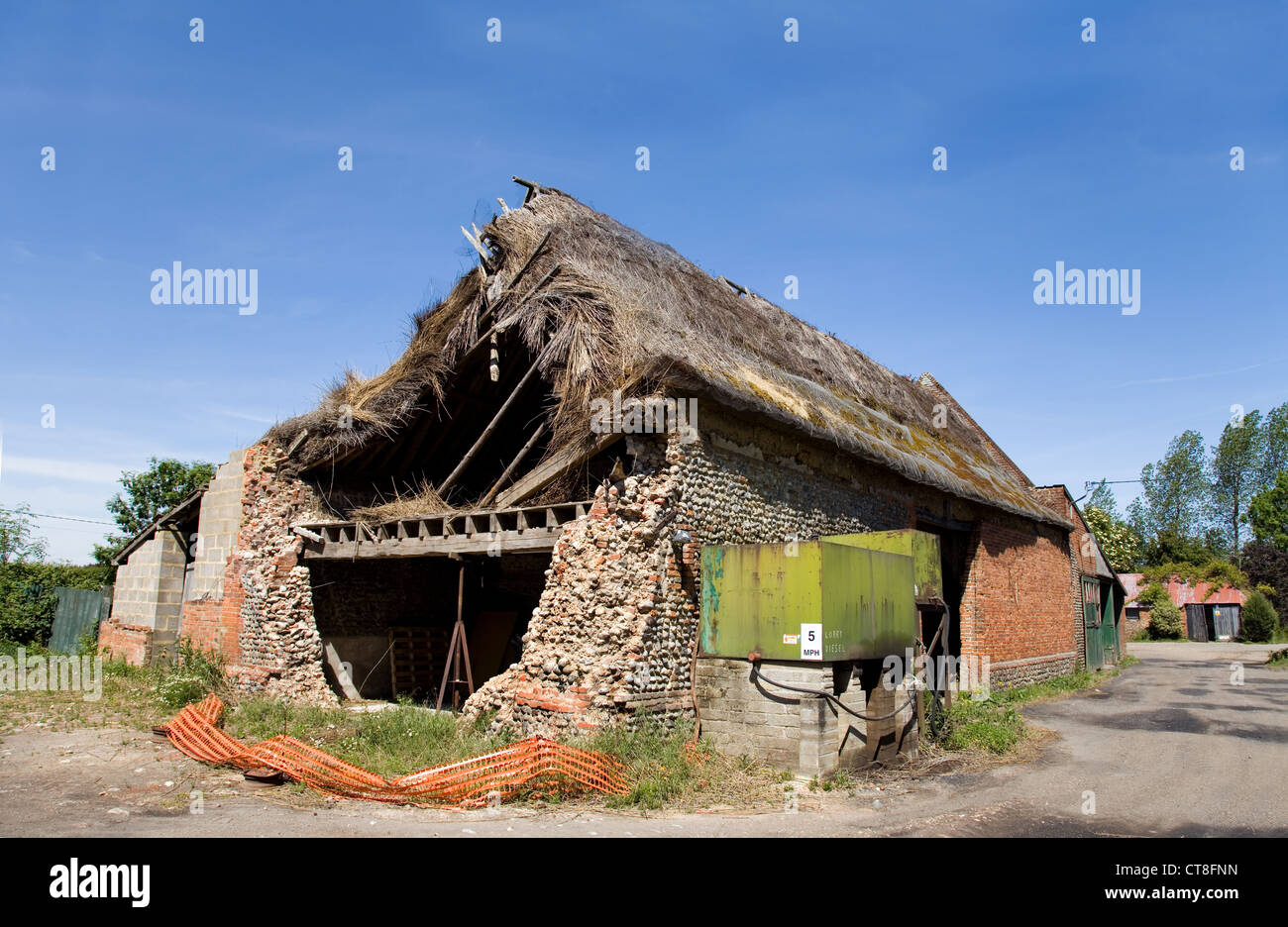 Con il tetto di paglia vecchia & piastrellate farm barn che sta crollando in una fattoria cantiere in rural Norfolk,UK. Visto qui con un combustibile diesel serbatoio di stoccaggio Foto Stock
