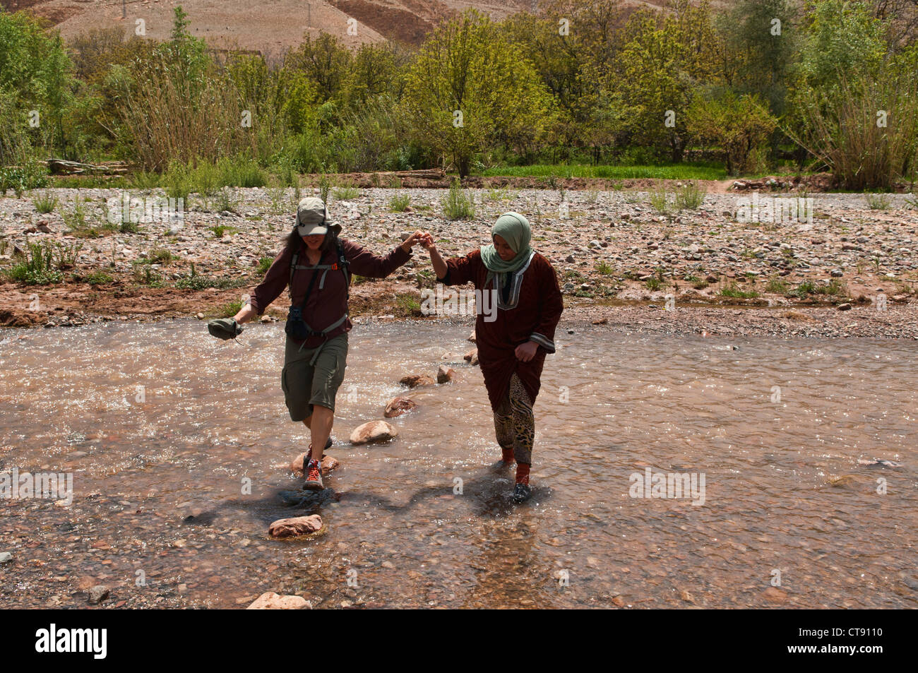 Attraversare un fiume durante il trekking del sud montagne Atlas, Marocco Foto Stock