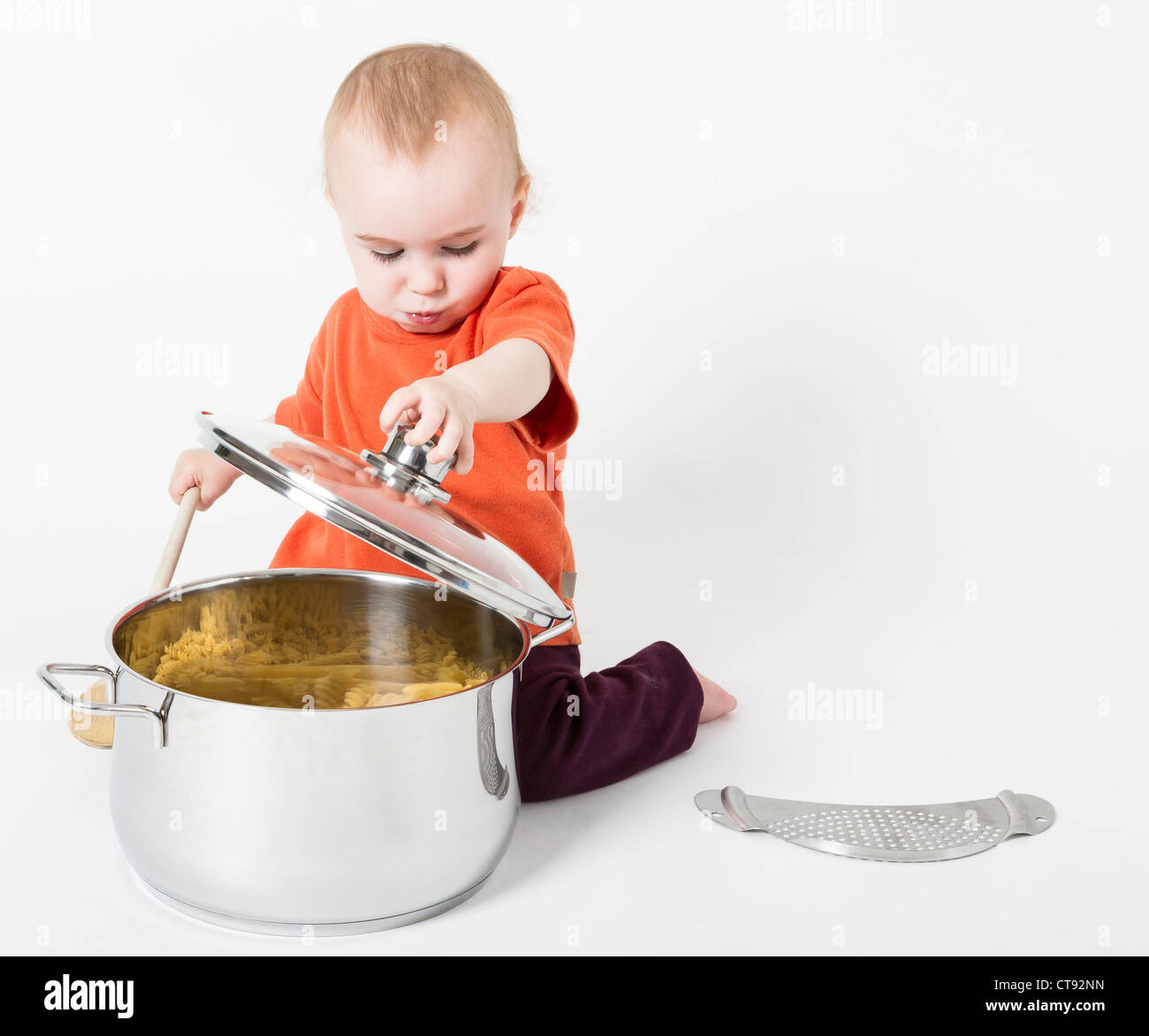 Bambino con grande pentola di cottura in sfondo grigio neutro Foto Stock