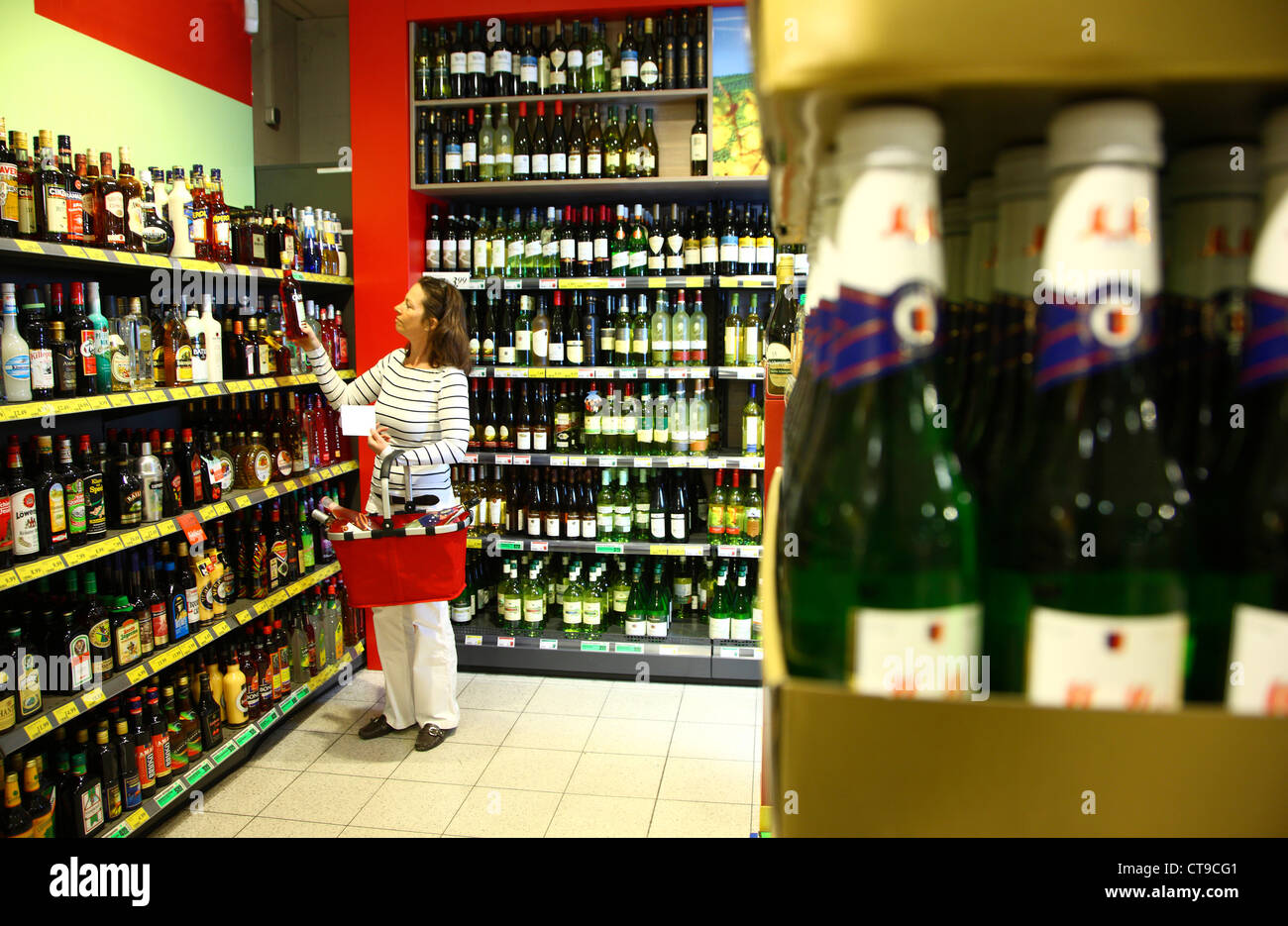 La donna è lo shopping in un grande supermercato. Dipartimento di bevande, bevande alcoliche, alcolici, vino, champagne. Foto Stock