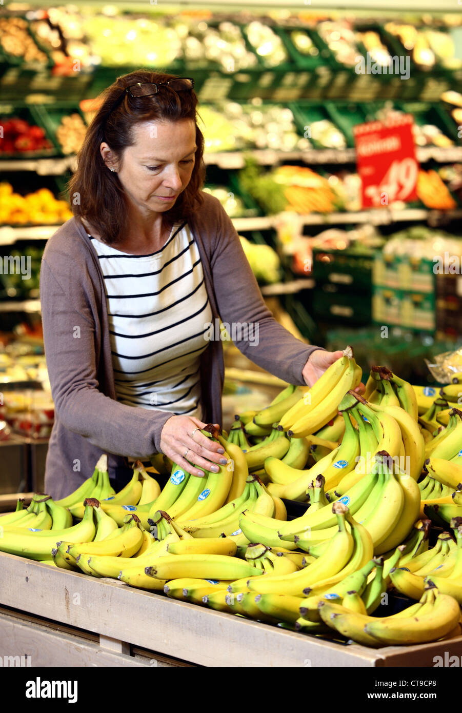 La donna è lo shopping in un grande supermercato. La frutta e la verdura al reparto. Foto Stock