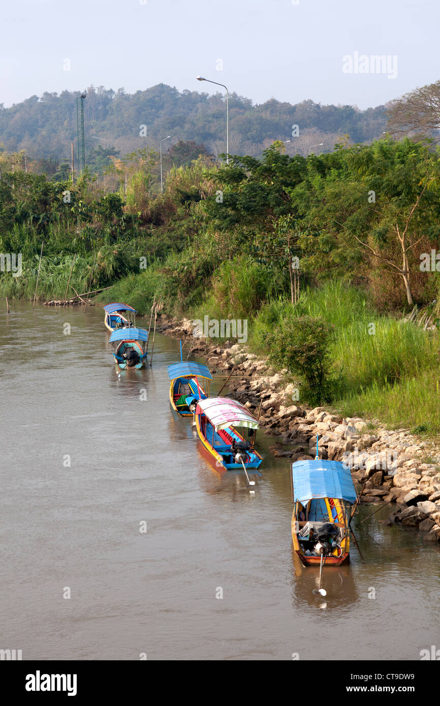 Lunga coda di barche ormeggiate su una banca del fiume Kok, a Chiang Rai (Thailandia). Bateaux à longue queue sur la rivière Kok. Foto Stock