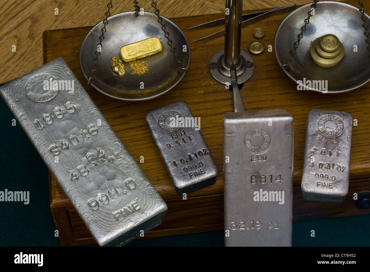 Silver bullion bars - Oro Bar, Pepita d'oro e polvere d oro su antiche Bilancia. Pesi in ottone sul lato opposto Foto Stock