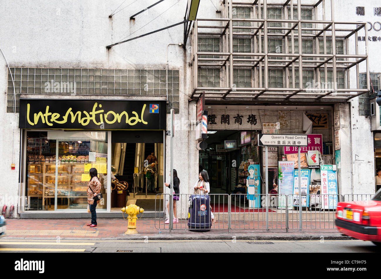 Strada tipica scena su Queens Road direzione centrale Western con Wellcome e Parkn Shop supermercati. Foto Stock