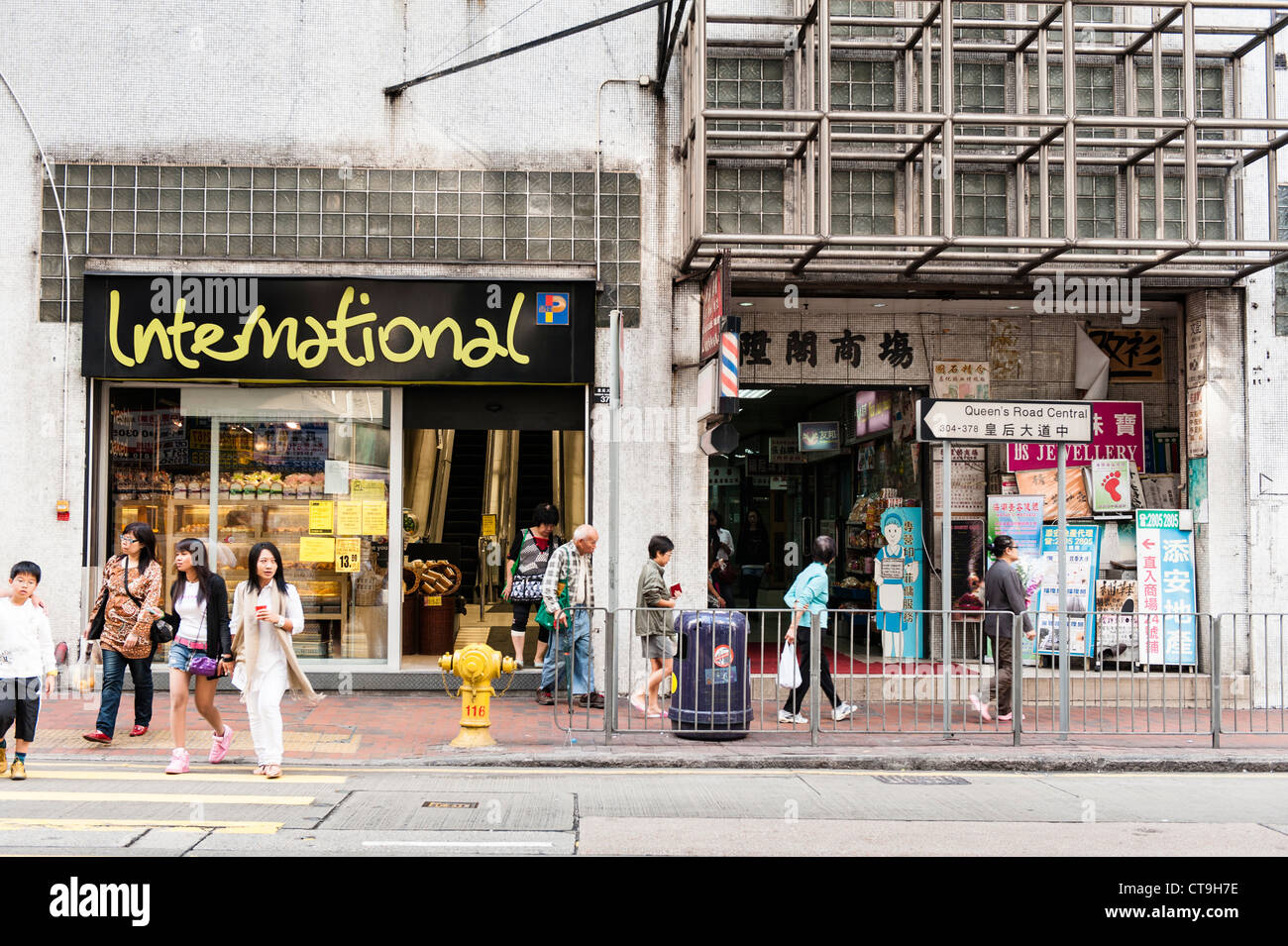 Strada tipica scena su Queens Road direzione centrale Western con Wellcome e Parkn Shop supermercati. Foto Stock