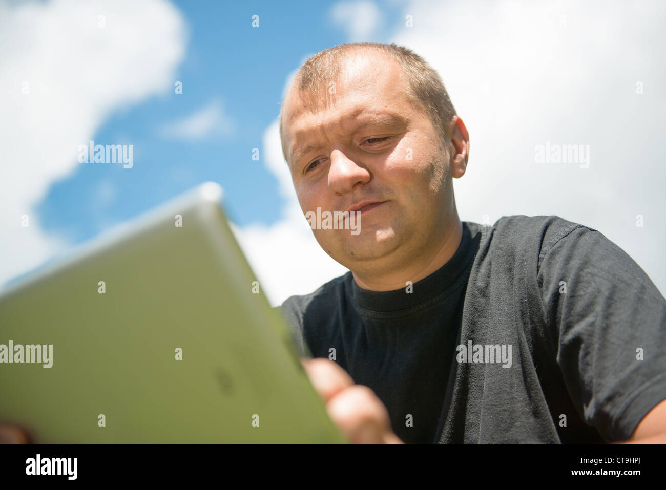 Giovane serio lavoro con ipad (tablet pc) contro il cielo blu Foto Stock