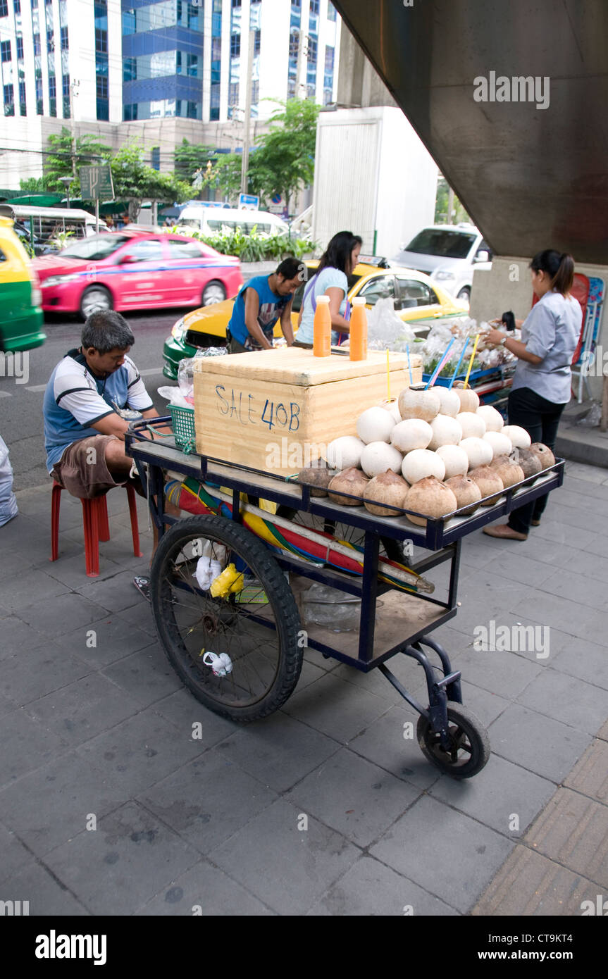 Un titolare di stallo e la sua pressione di stallo di noce di cocco in Sukhumvit Road, Bangkok, Thailandia Foto Stock