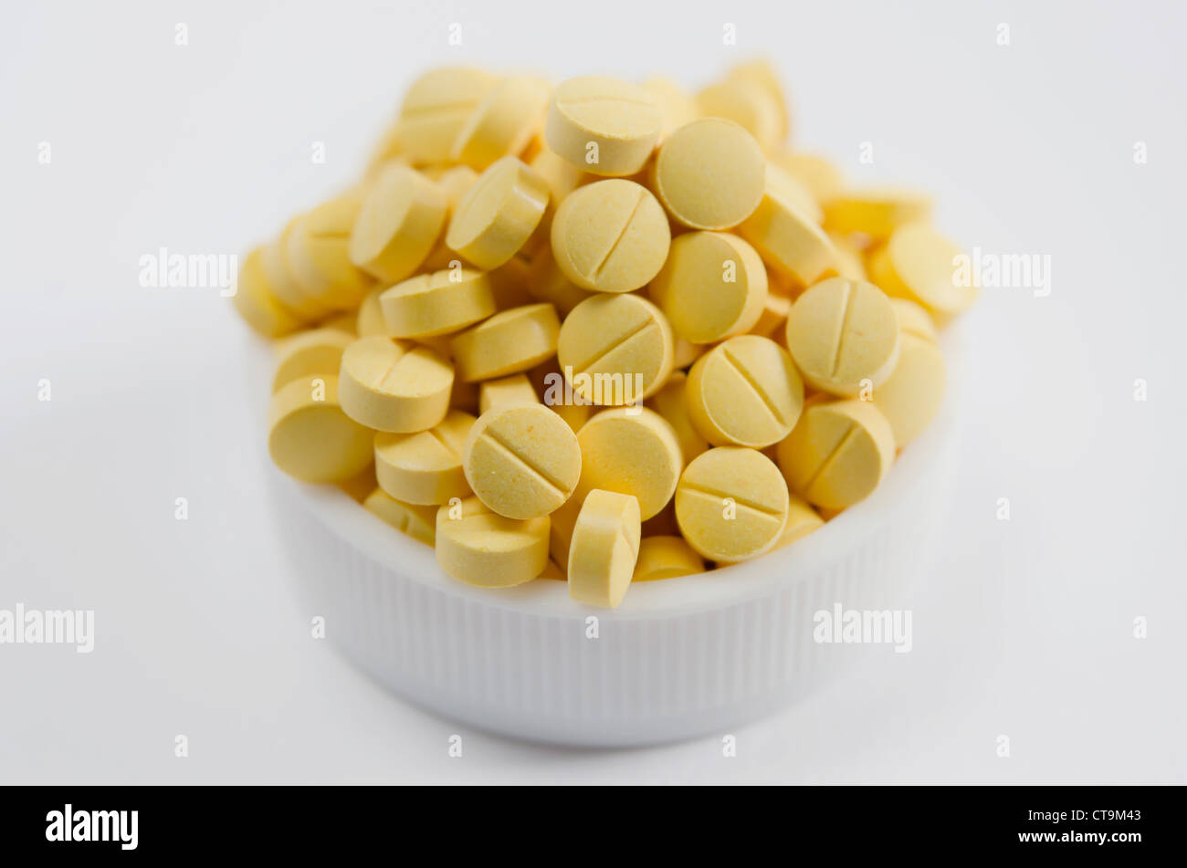 Close-up di pillole di colore giallo su sfondo bianco Foto Stock