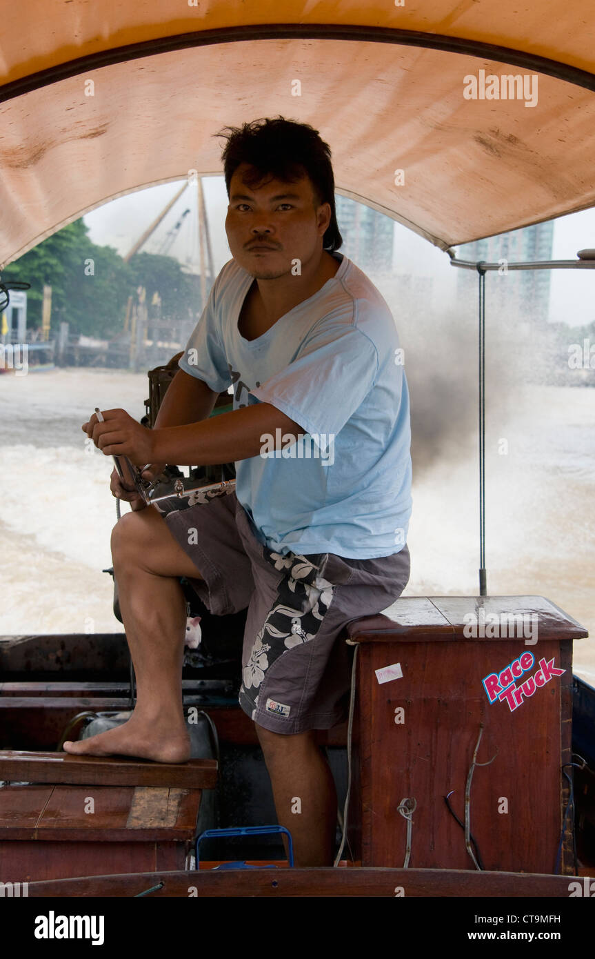 Un comandante di una lunga coda di barca al timone sul Fiume Chao Praya river in Bangkok, Tailandia. Foto Stock