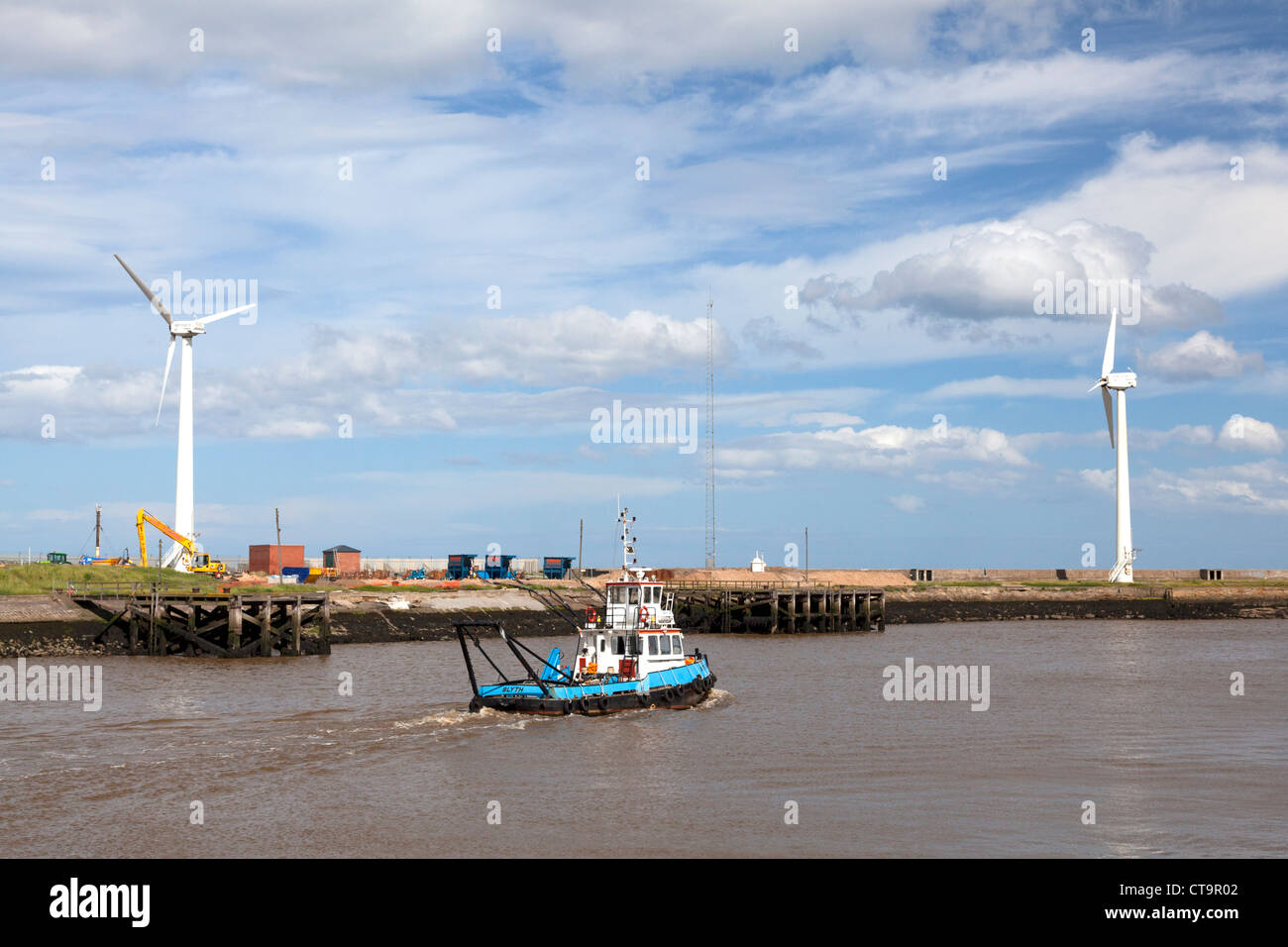 Il rimorchiatore "Blyth adoperano' di lasciare il porto, con turbine eoliche sulla riva, Blyth, Northumberland Foto Stock