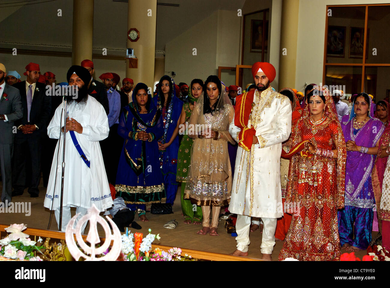 Tradizionale Indiano orientale matrimonio santo uomo sposo sposa matrimonio valutazione in piedi sul pavimento del tempio sikh Foto Stock