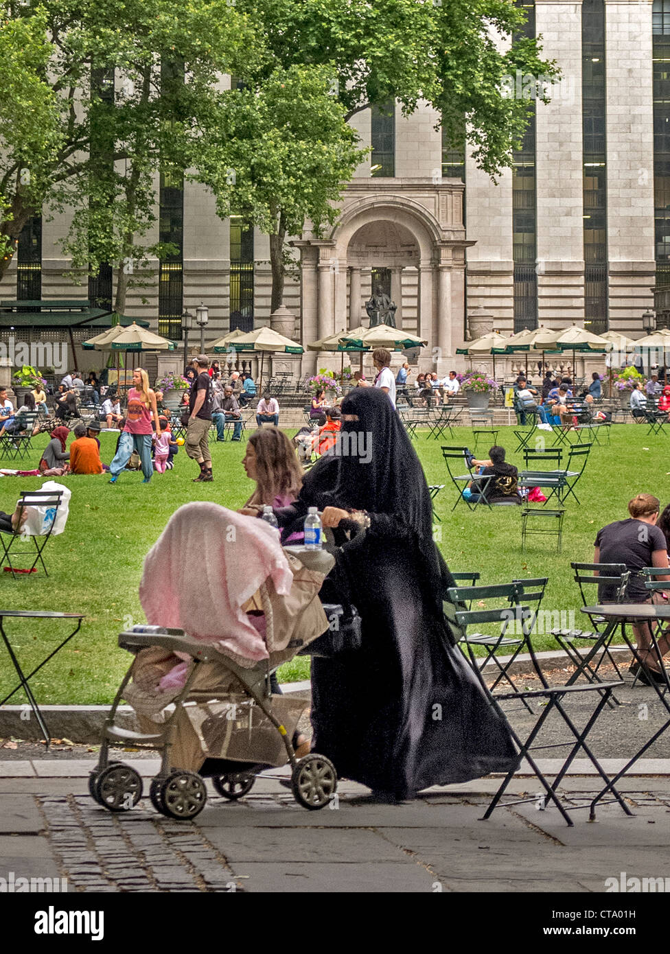 Un sistema completamente donna musulmana velata spinge un passeggino in Bryant Park di New York City. Nota Biblioteca Pubblica di New York in background. Foto Stock