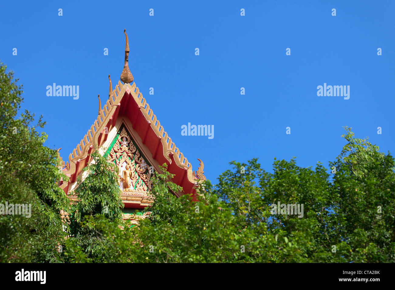 Il tetto di un buddista tailandese monastero sopra gli alberi Foto Stock